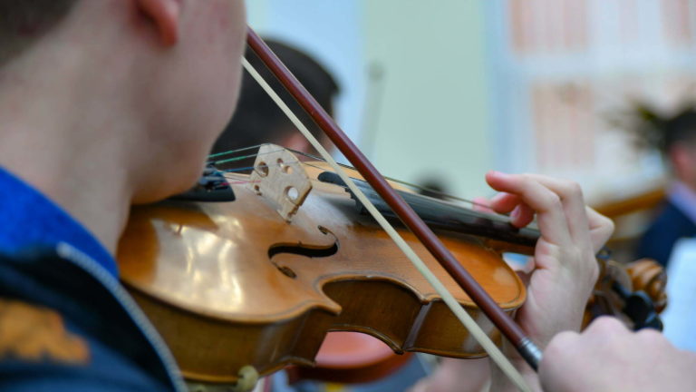 A young musician plays the violin in a symphony orchestra.